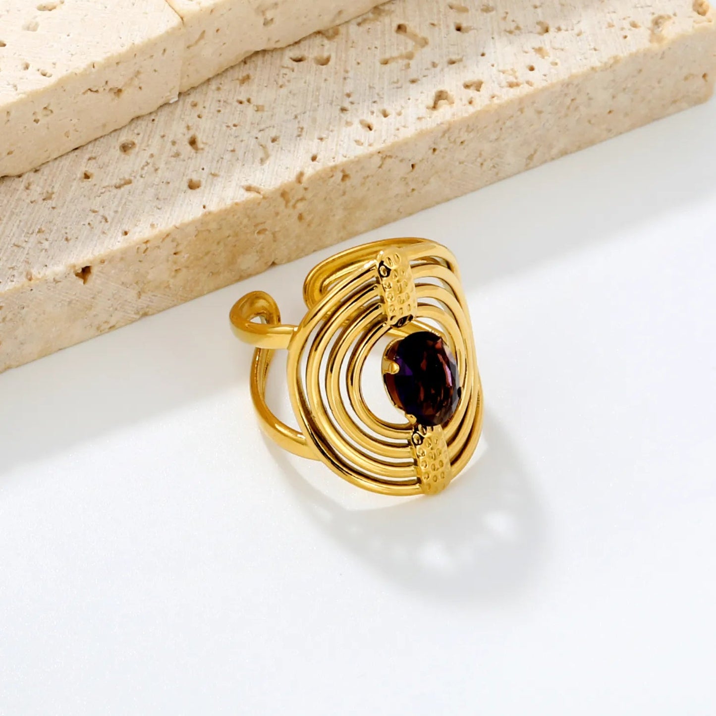 Striking Contrast Between Rough Textured Gold and Smooth Faceted Gemstone
